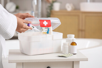 Wall Mural - Woman taking thermometer from home first aid kit in bathroom, closeup