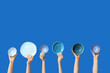 © Pixel-Shot - Hands holding empty plates on blue background