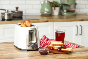 White toaster and wooden plate with bread slices on table in kitchen