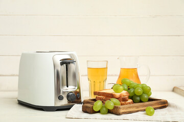 Wall Mural - Modern toaster with bread slices and grapes on white wooden background