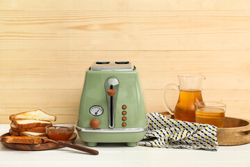 Canvas Print - Green toaster with bread slices, jug and glass of juice on white wooden table