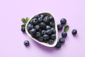 Sticker - Bowl of fresh ripe blueberry on lilac background, closeup