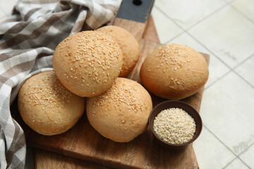 Wall Mural - Wooden board of fresh buns with sesame seeds on white tile background