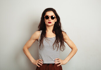 Wall Mural - Success sexy  woman posing in fashion sunglasses and stripped t-shirt with red lipstick on white wall background with empty copy space. Fashion lifestyle