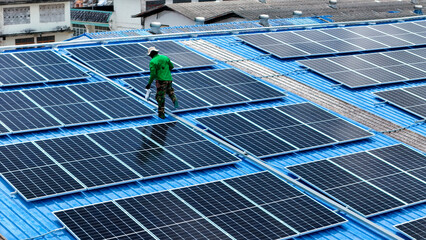 Wall Mural - top aerial of engineer men inspects construction of solar cell panel or photovoltaic cell at roof top. Industrial Renewable energy of green power. factory at urban area. worker working on tower roof.