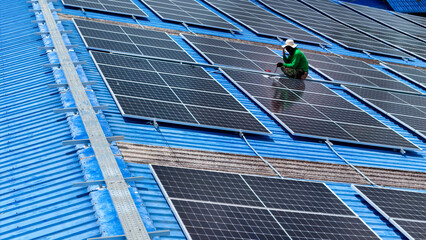 Wall Mural - top aerial of engineer men inspects construction of solar cell panel or photovoltaic cell at roof top. Industrial Renewable energy of green power. factory at urban area. worker working on tower roof.