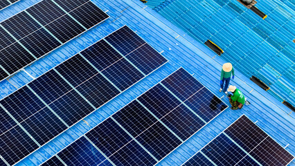 Wall Mural - top aerial of engineer men inspects construction of solar cell panel or photovoltaic cell at roof top. Industrial Renewable energy of green power. factory at urban area. worker working on tower roof.