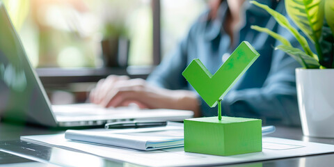 Green check mark on desk, woman working in blurred background