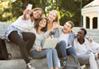 © Prostock-studio - Happy international students taking selfie on smartphone while studying with laptop in city, sitting on stairs