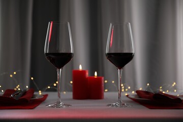 Wall Mural - Burning candles and wine in glasses on table against blurred lights