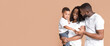 © Prostock-studio - Young black parents bonding with their little son over yellow background in studio, free space