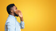 © Prostock-studio - Profile portrait of black guy making announcement, shouting at copy space on yellow studio background, sharing news.