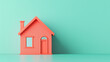 © patpongstock - A vibrant coral house model stands against a mint green background, symbolizing modern architecture and home design.