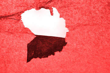 Torn hole on a sheet of red paper isolated on a transparent background.  torn paper on gray background. realistic hole torn in white paper  and transparent backdrop.