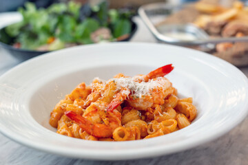 A delectable serving of macaroni, generously coated in a rich and savory tomato sauce, perfectly complemented by succulent shrimp and melted cheese.