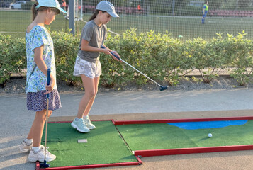 teenage girls play mini golf