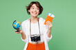 © ViDi Studio - Traveler fun woman wear casual clothes hold passport ticket globe look aside on area isolated on plain green background. Tourist travel abroad in free spare time rest getaway. Air flight trip concept.