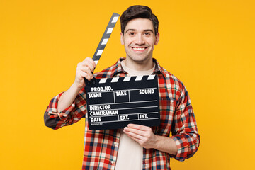 Poster - Young smiling happy man he wears red checkered shirt casual clothes hold in hand classic black film making clapperboard isolated on plain yellow orange background studio portrait. Lifestyle concept.