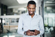 © peopleimages.com - Black man, phone and happy in office for communication, investment and business email with coffee. Human resources, technology and smile for recruitment, social networking and talent acquisition