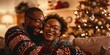 © KM - A couple wearing matching Christmas sweaters, laughing and cuddling in a warmly lit living room decorated for the holidays.
