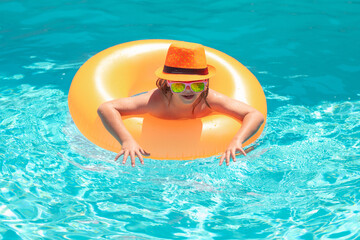 Wall Mural - Children playing in pool. Child in swim pool on inflatable ring. Swimming pool.