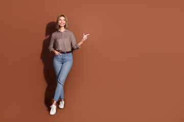 Poster - Photo of lovely cute woman wear stylish clothes demonstrate empty space isolated on brown color background