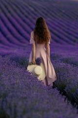 Canvas Print - A woman is walking through a field of lavender flowers