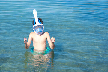 Teenage boy enjoying snorkeling in sea water, shows size fish with hands, active summer holidays, exploring underwater life with mask and snorkel, Water activities, childhood adventure, marine life