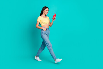 Poster - Full body portrait of pretty young woman walk use smart phone wear top isolated on turquoise color background