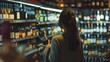 © liliyabatyrova - A woman contemplates her choice as she examines a wine bottle amidst the warm glow of a quaint wine shop