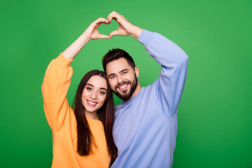 Canvas Print - Photo of happy lovely couple wear stylish clothes arms above head heart shape isolated on green color background