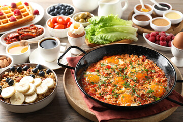 Sticker - Tasty shakshouka in frying pan and other meals served for breakfast on wooden table