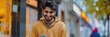© TheWaterMeloonProjec - Cheerful young man from South Asia or the Middle East, a freelancer or student, engaging with friends on social networks through his smartphone, texting and browsing online with a friendly smile.