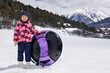© Studio Peace - In winter, a happy little girl rides snow tubing, inflatable slide in the mountains.