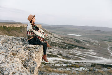 Wall Mural - Serene woman sitting on cliff edge overlooking vast yellowstone valley in tranquil solitude