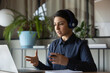 © fizkes - Concentrated Indian female employee in wireless earphones talk on video call using modern laptop, ethnic woman worker in headphones have webCam conversation or conference, consult client online