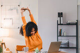 African American woman stretching her arms while taking break from working on laptop at home.