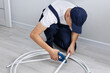© Studio Peace - Construction worker in uniform cuts a PVC pipe during renovation in an apartment.