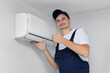 © Studio Peace - Professional technician gives a thumbs up and smiles after installing a modern air conditioner.