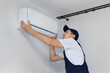 © Studio Peace - Professional technician who installs and maintains a modern indoor air conditioner.