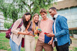 © Jose Calsina - group of students happily sharing content on social media using a cellphone app. friends engrossed in their smartphones. Multiracial teenagers browsing the internet on campus with their mobile phones