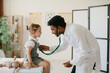 © dsheremeta - Attractive cheerful male Asian doctor listens to little girl with stethoscope.