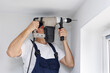© Studio Peace - Builder in uniform uses a hammer drill to make a hole in the wall in the apartment.