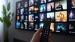 © Nathaphat - Choosing Movie to Stream: Person Using Smart Remote on TV Screen with Diverse Options