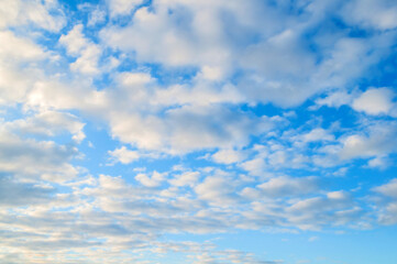 Blue sky background with white colorful clouds and soft sunlight