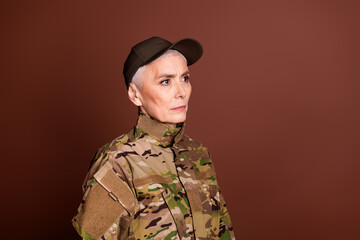 Poster - Photo of confident strong retired woman wear camouflage looking empty space isolated brown color background