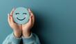 © Emqan - Blue Smiley Face Sticker in Child's Hands on Blue Background, Positive Vibes Concept