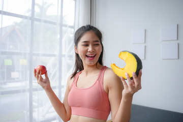 Wall Mural - Happy asian woman holding an apple and a slice of pumpkin smiling for a healthy lifestyle