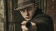 © Iswanto - A man in a fedora points a gun directly at the camera. The man is wearing a dark coat and is standing in front of a textured wall.