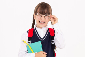 A cute schoolgirl in school uniform holds notebook and pen in her hand.